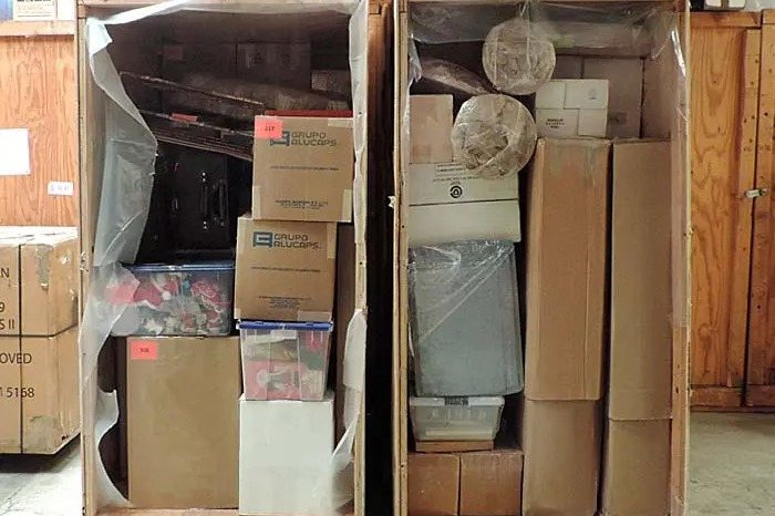 Zwei geöffnete Lager-Holzkisten mit Umzugskartons und verpackten Möbeln